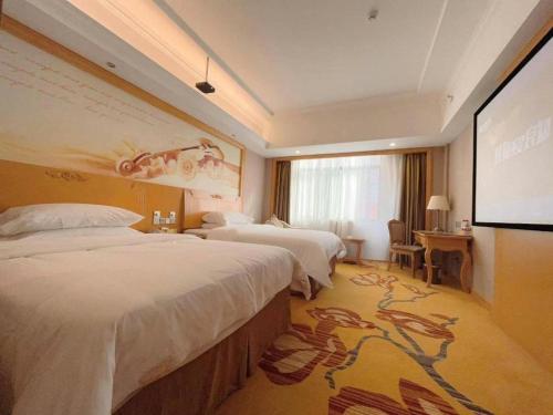 a hotel room with two beds and a projection screen at Vienna Hotel Guangxi Fangcheng in Fangcheng