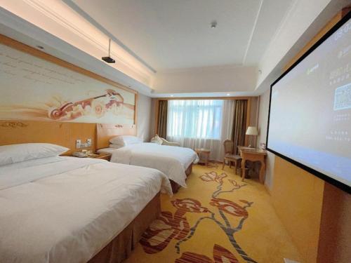 a hotel room with two beds and a projection screen at Vienna Hotel Guangxi Fangcheng in Fangcheng