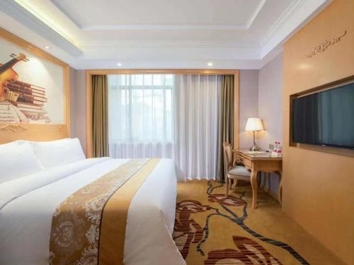 a hotel room with a bed and a desk and a television at Vienna Hotel Guangxi Fangcheng in Fangcheng
