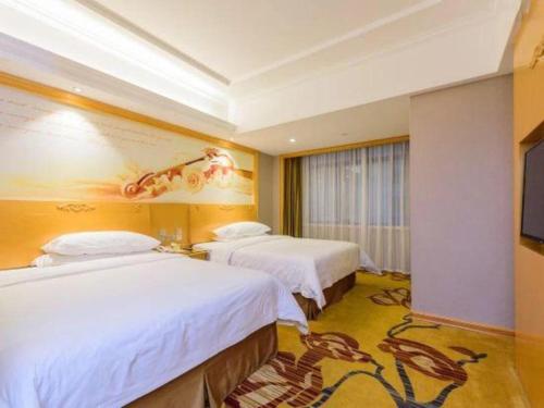 a hotel room with two beds and a painting on the wall at Vienna Hotel Guangxi Fangcheng in Fangcheng