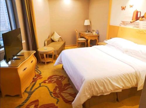 a hotel room with a bed and a flat screen tv at Vienna Hotel Guangxi Fangcheng in Fangcheng