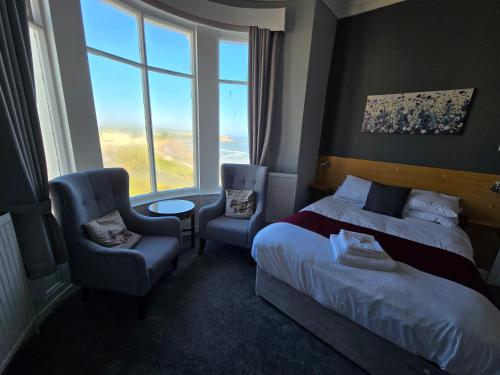 a hotel room with a bed and a chair and a window at Boston Hotel in Scarborough
