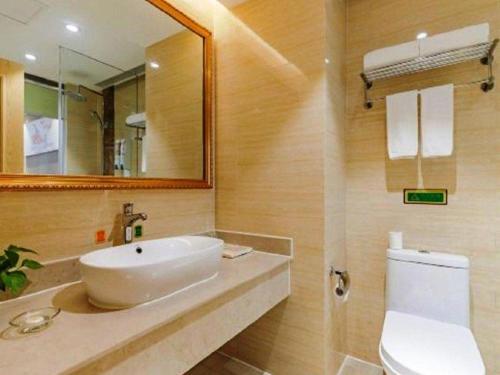 a bathroom with a sink and a mirror and a toilet at Vienna Hotel Anhui Taihe Baitai Xingma International in Taihe
