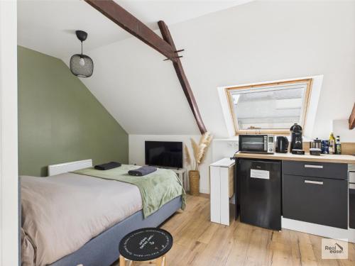 a small bedroom with a bed and a kitchen at Logement de caractère en haute ville de Quimperlé in Quimperlé