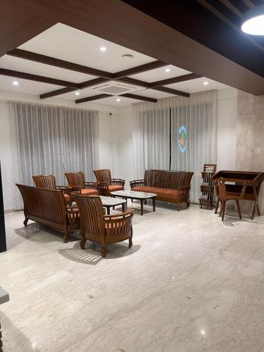 a large room with wooden chairs and tables and a room with tables and benches at Rathna Residency in Tiruppattūr