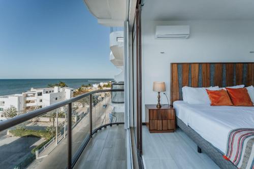 a bedroom with a bed and a balcony with the ocean at Penthouse en Chicxulub in Chicxulub