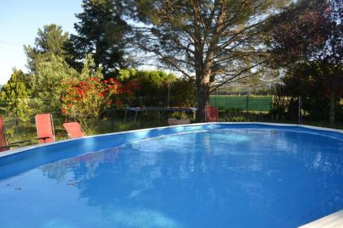 - une piscine bleue avec 2 chaises et une table dans l'établissement Maison familiale Drôme - Ardèche, à Châteauneuf-du-Rhône