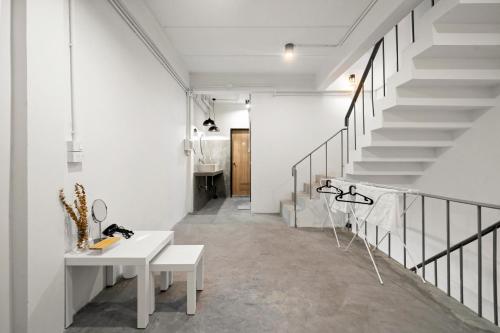 a white hallway with stairs and a white table at Kuha Phuket Old Town in Phuket Town