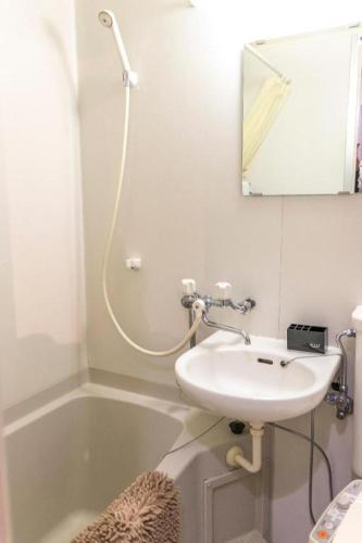 a bathroom with a sink and a bath tub with a mirror at HOSTEL LUND I -Oimachi- in Tokyo