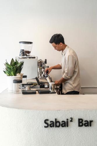 a man standing in front of a machine on a counter at Kuha Phuket Old Town in Phuket Town