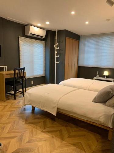 a bedroom with two beds and a table and a desk at HOSTEL LUND I -Oimachi- in Tokyo