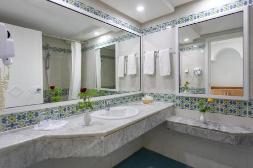 a bathroom with two sinks and two mirrors at Djerba Holiday Beach in Midoun