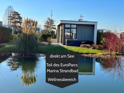 a house that is sitting on top of a pond at Ferienhaus 55 am Wasser Olburgen - perfekt für Familien - mit Freibad, Sauna, Restaurant und Spielplatz in Olburgen