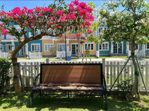 a bench sitting under a tree with pink flowers at Chillin Villa Novaworld Phan Thiet in Bình Tú