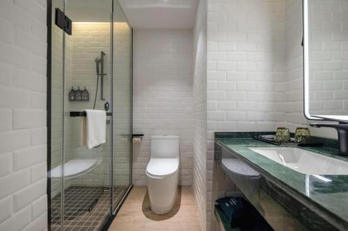 une salle de bain avec toilettes, lavabo et douche dans l'établissement City Comfort Premier Hotel Qinzhou Lingshan Traditional Chinese Medicine Hospital Gymnasium, à Lingshan