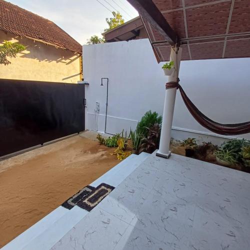 an empty backyard with a white wall and a fence at Salty Palm Villa in Arugam Bay