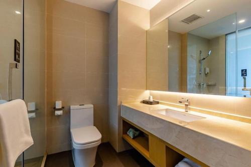 a bathroom with a sink and a toilet and a mirror at City Comfort Inn Hefei Wulimiao Feihe Road in Hefei