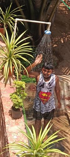 a man is standing in a garden with a bucket at Srujana Beach Homestay in Gokarn