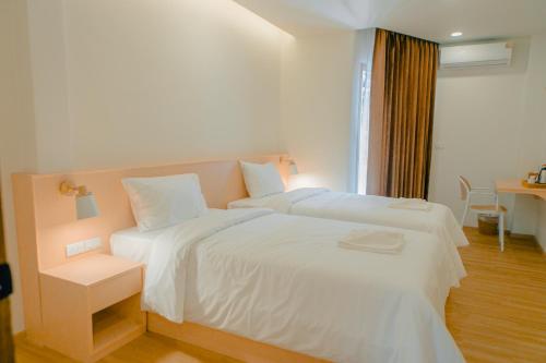 a white bedroom with two beds and a table at Baan Cocoa Boutique Hotel in Natai Beach