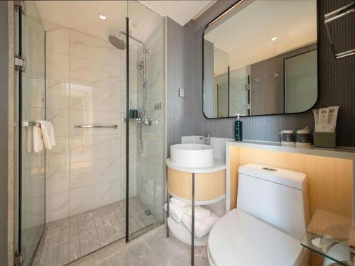 a bathroom with a shower and a toilet and a sink at Magnotel Changsha Wuyi Square Metro Station National Finacial Center in Changsha