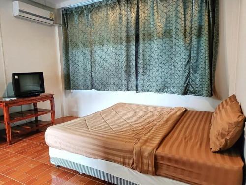 a bedroom with a bed and a television and a window at Piyaporn Hill Paradise Hotel in Mae Sai