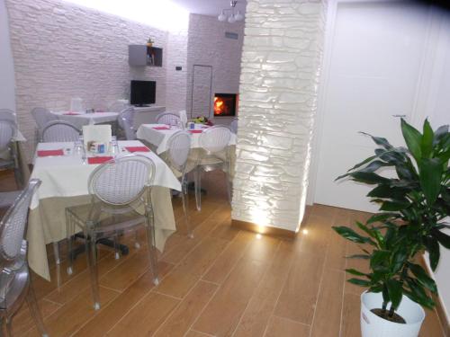 a dining room with white tables and chairs and a fireplace at Agriturismo Nonna Rosa in Matera