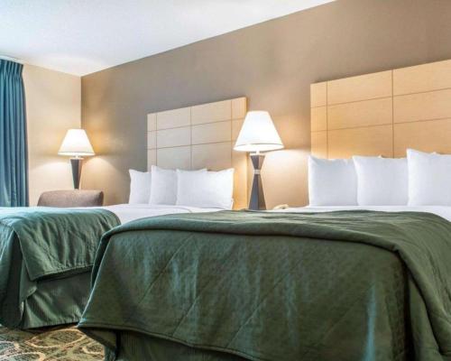 two beds with green sheets in a hotel room at Quality Inn in Geneseo