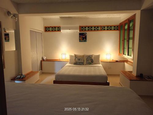 a bedroom with a bed and two windows at Posada Refugio de la Luna in Providencia