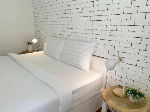 a white bedroom with a bed with a white brick wall at Charisma Resort in Ratchaburi