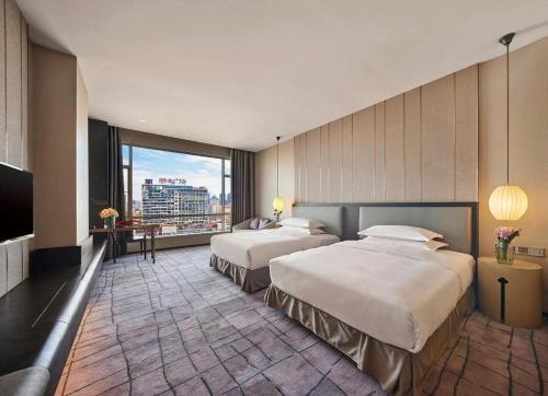 東莞市にあるDongGuan JOYC Hotel のベッドが2つと大きな窓があるホテルの部屋