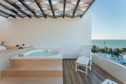 a room with a tub and a chair and the ocean at Penthouse en Chicxulub in Chicxulub