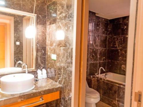 a bathroom with a sink and a toilet and a mirror at Ocean Spring Metropark Hotel Zhuhai in Zhuhai