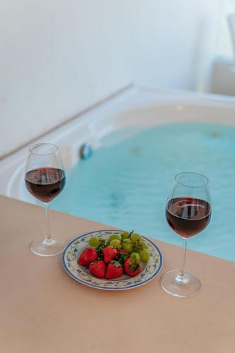 two glasses of wine and a plate of fruit next to a swimming pool at Penthouse en Chicxulub in Chicxulub