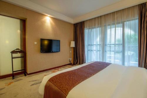 a hotel room with a bed and a flat screen tv at Ocean Spring Metropark Hotel Zhuhai in Zhuhai