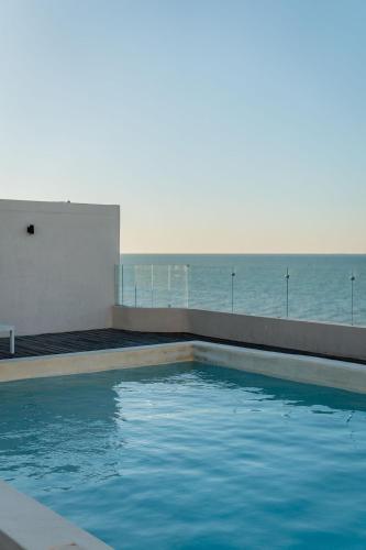 a swimming pool with the ocean in the background at Penthouse en Chicxulub in Chicxulub