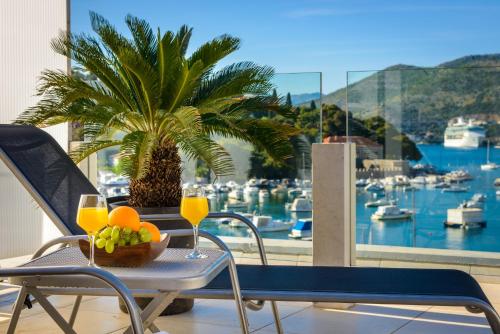 a table with glasses of orange juice and a palm tree on a balcony at Adriatic Deluxe Apartments in Dubrovnik