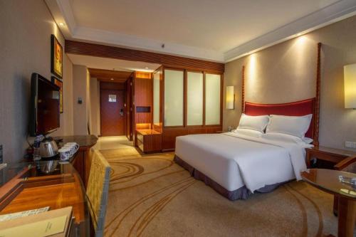 a bedroom with a large white bed and a television at Ocean Spring Metropark Hotel Zhuhai in Zhuhai
