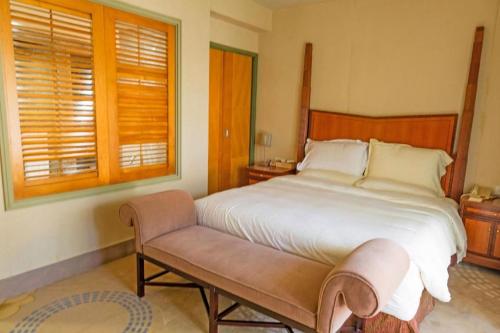 a bedroom with a large bed and a bench at Ocean Spring Metropark Hotel Zhuhai in Zhuhai