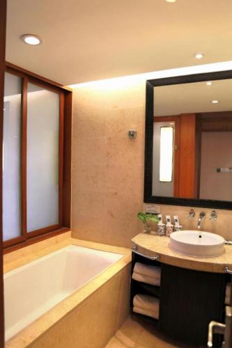 a bathroom with a tub and a sink and a mirror at Ocean Spring Metropark Hotel Zhuhai in Zhuhai