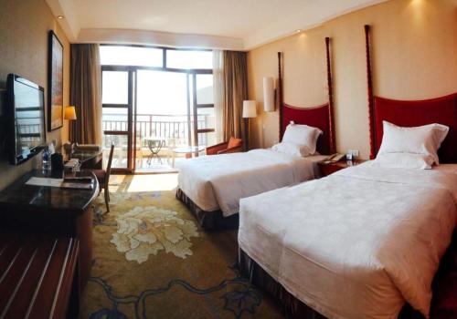 a hotel room with two beds and a balcony at Ocean Spring Metropark Hotel Zhuhai in Zhuhai