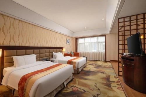 a hotel room with two beds and a flat screen tv at Fu Yuan Hotel in Dongguan