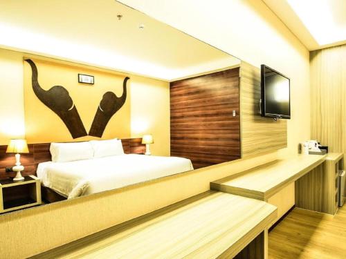 a hotel room with a bed and a flat screen tv at Alvarez Hotel in Buriram