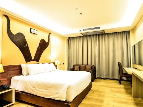 a hotel room with a large bed and a desk at Alvarez Hotel in Buriram