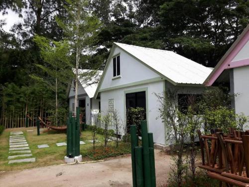 a white house with green posts in front of it at Khao Yai the kids adventure in Mu Si