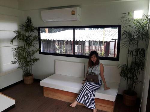 a woman sitting on a white bench in front of a window at Khao Yai the kids adventure in Mu Si