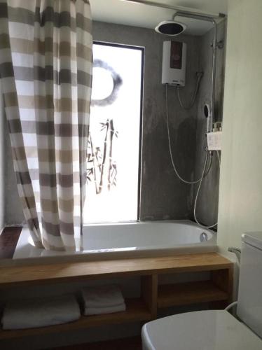 a bathroom with a tub and a toilet and a window at Khao Yai the kids adventure in Mu Si