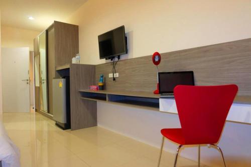 a room with a red chair and a desk with a television at The Pride in Nakhon Pathom