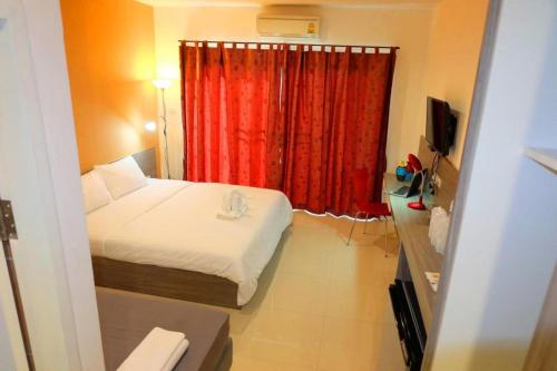 a hotel room with a bed and a red curtain at The Pride in Nakhon Pathom