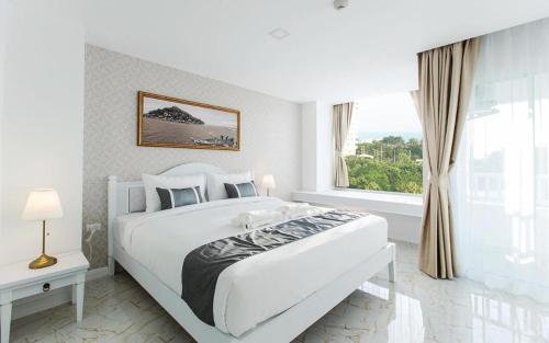ein weißes Schlafzimmer mit einem großen Bett und einem Fenster in der Unterkunft B2 Hua Hin Premier Hotel in Hua Hin