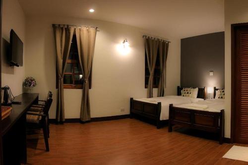 a bedroom with two beds and a wooden floor at Phumin Place Hotel in Nan